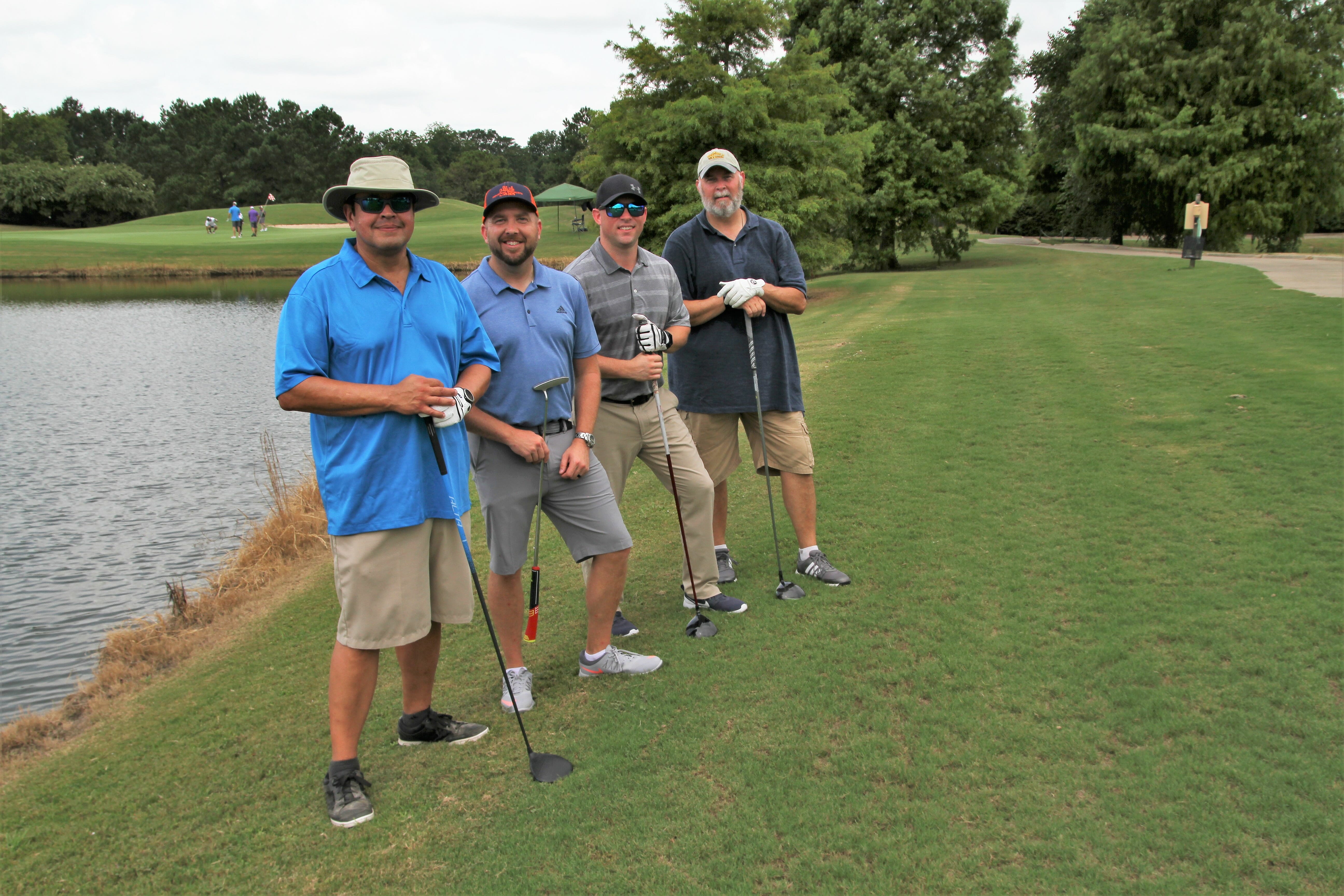 four men holding golf clubs